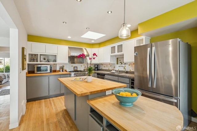 kitchen featuring hanging light fixtures, stainless steel appliances, a center island, and white cabinets