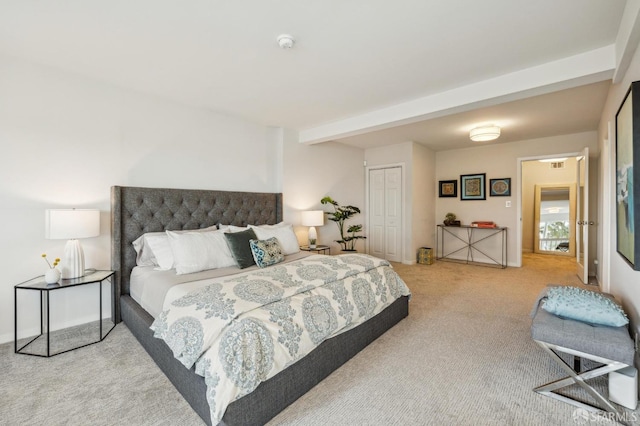 carpeted bedroom with a closet and beamed ceiling