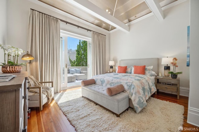 bedroom with access to exterior, beam ceiling, baseboards, and wood finished floors