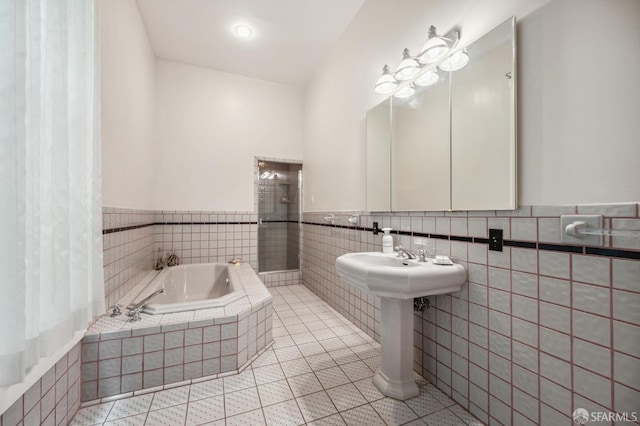 full bathroom featuring tile patterned floors, a wainscoted wall, tile walls, and a garden tub