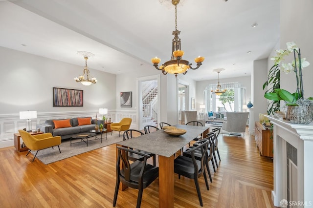 dining space featuring a chandelier, a wainscoted wall, light wood-style flooring, and stairway