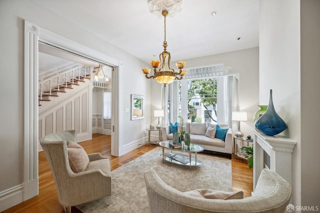 living area with a chandelier, stairway, baseboards, and wood finished floors