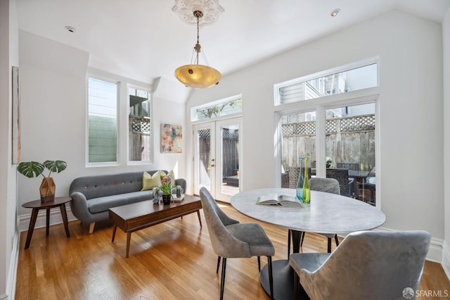 dining room with wood finished floors, french doors, and vaulted ceiling