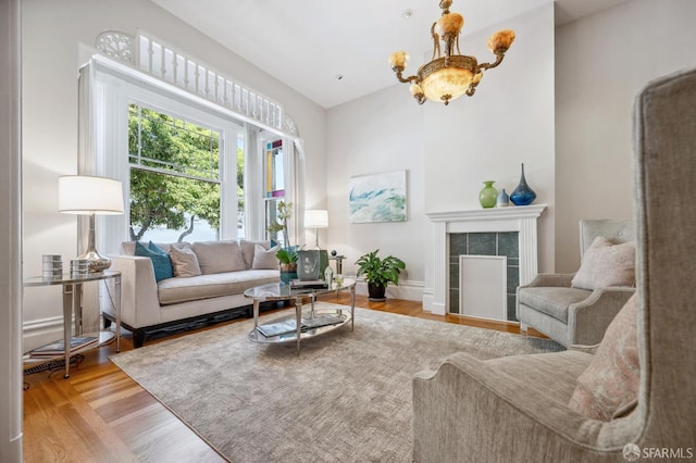 living area featuring wood finished floors, a chandelier, and a tile fireplace