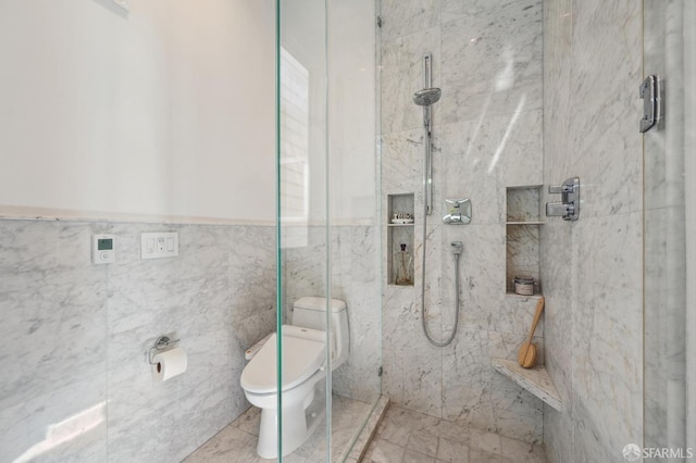 full bath featuring tile walls, toilet, a marble finish shower, and wainscoting