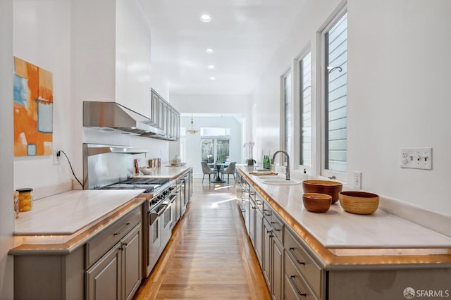 kitchen featuring a sink, double oven range, recessed lighting, light wood-style floors, and light countertops