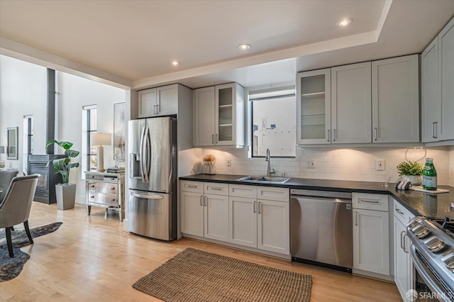 kitchen featuring appliances with stainless steel finishes, sink, light wood-type flooring, and decorative backsplash