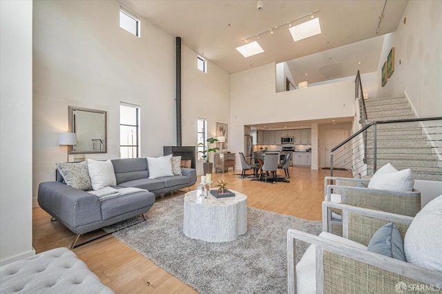 living room with hardwood / wood-style flooring, track lighting, a skylight, and a wood stove