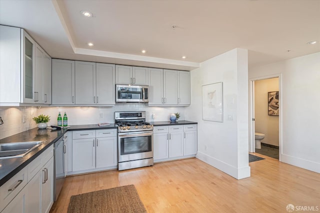 kitchen with stainless steel appliances, light hardwood / wood-style floors, sink, and backsplash