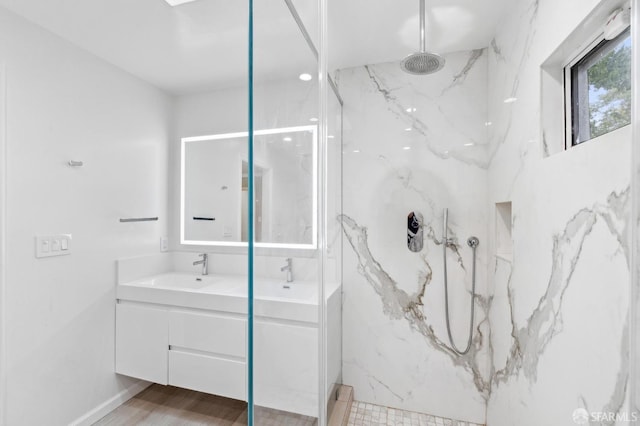 bathroom with double vanity, a marble finish shower, a sink, and wood finished floors