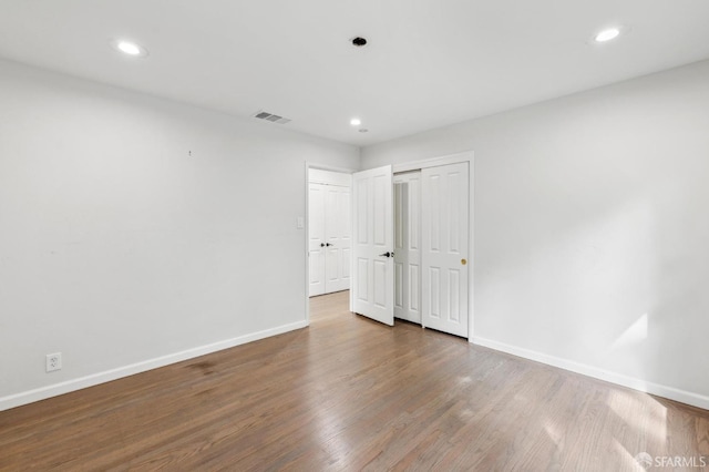 unfurnished bedroom with recessed lighting, wood finished floors, visible vents, and baseboards