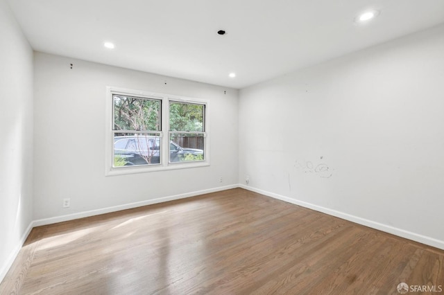 spare room featuring recessed lighting, wood finished floors, and baseboards