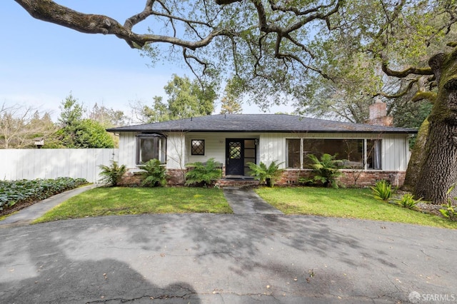 view of front of house with a front yard, brick siding, and fence