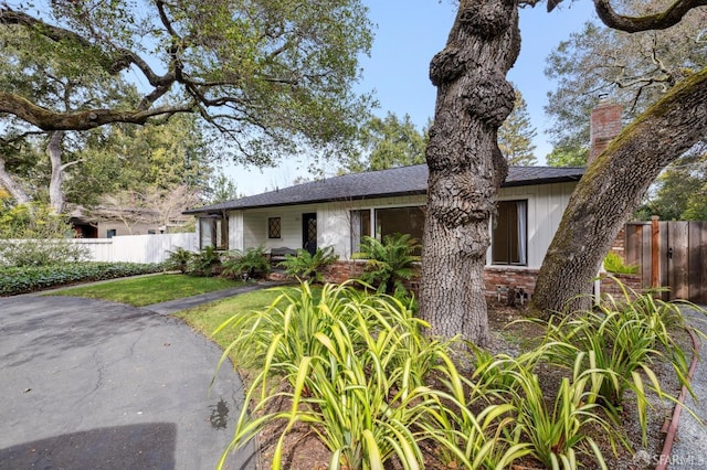 view of front facade with brick siding, a front yard, and fence