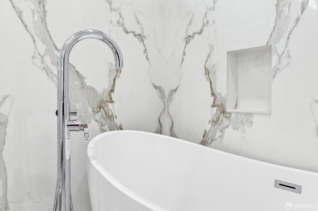 bathroom with a soaking tub and stone wall