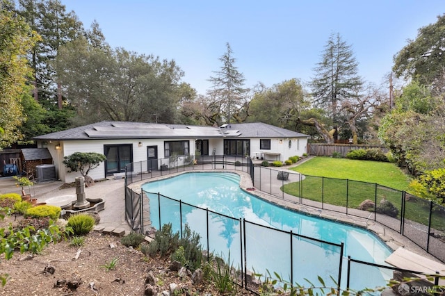 view of swimming pool with a patio, central AC, fence, a lawn, and a fenced in pool