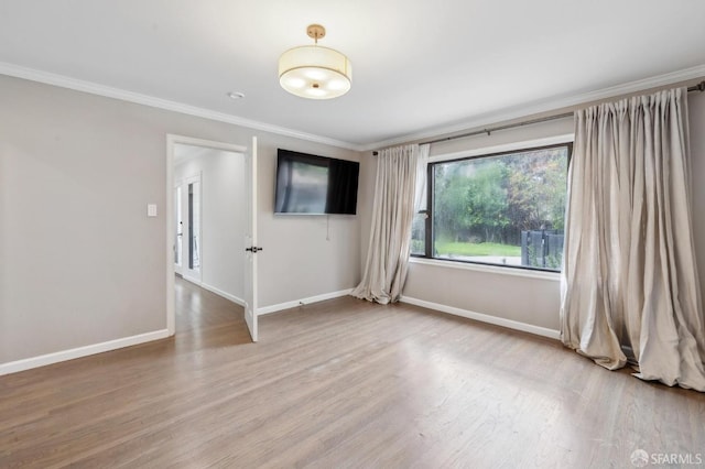 empty room featuring baseboards, wood finished floors, and crown molding