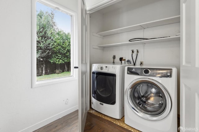 clothes washing area featuring dark wood-style floors, laundry area, washer and clothes dryer, and baseboards