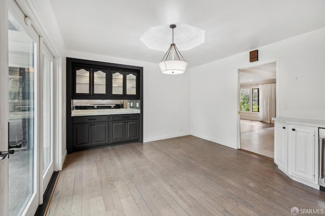 unfurnished dining area featuring light wood-type flooring and baseboards