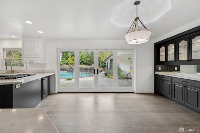 kitchen with light wood-style flooring, glass insert cabinets, hanging light fixtures, white cabinetry, and recessed lighting