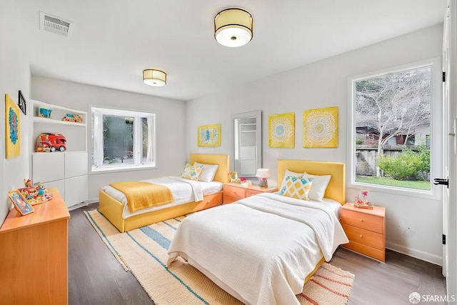 bedroom with visible vents, baseboards, and wood finished floors