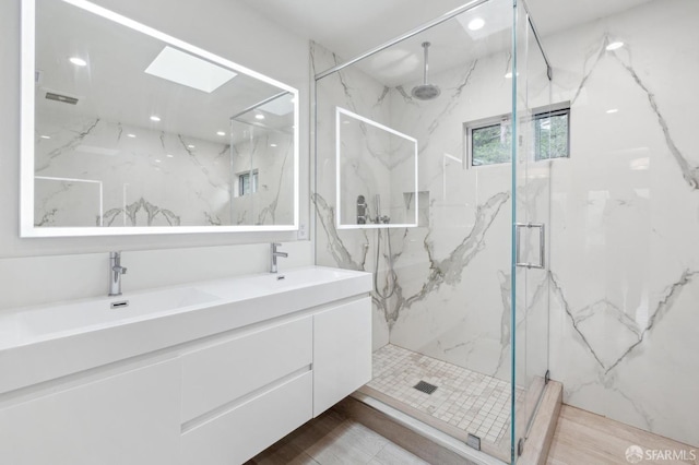 bathroom with a sink, a skylight, a marble finish shower, and recessed lighting