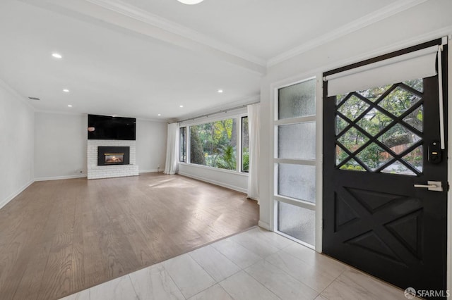 entrance foyer featuring a brick fireplace, baseboards, ornamental molding, and recessed lighting