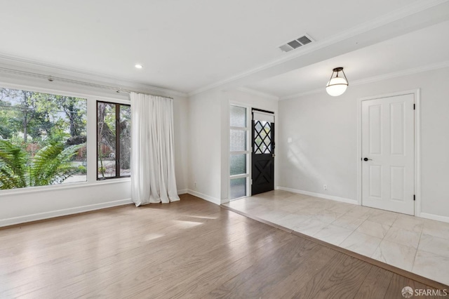 empty room featuring baseboards, light wood-style flooring, visible vents, and crown molding