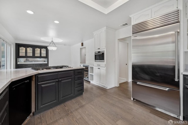 kitchen featuring appliances with stainless steel finishes, white cabinets, visible vents, and wood finished floors