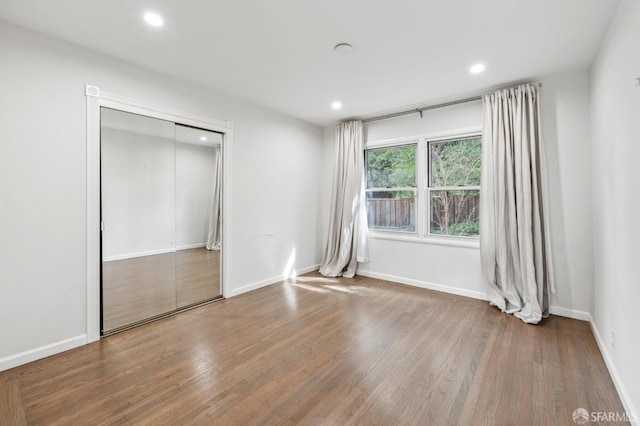 unfurnished bedroom featuring baseboards, wood finished floors, and recessed lighting