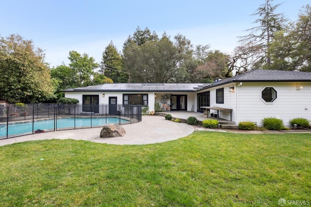 rear view of house featuring a yard, solar panels, a fenced in pool, and a patio