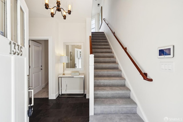 staircase with a notable chandelier