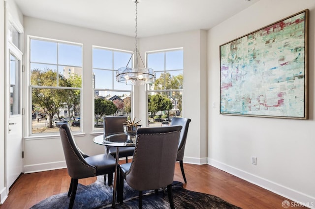 dining room with dark wood-type flooring and an inviting chandelier