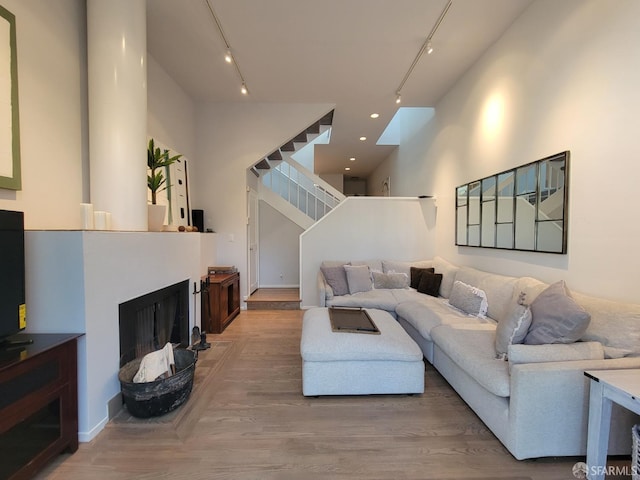 living room with wood-type flooring, rail lighting, and a high ceiling