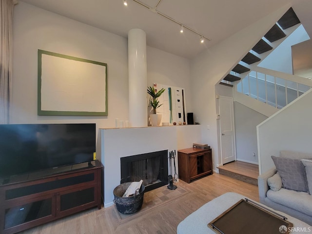 living room featuring a towering ceiling, rail lighting, and hardwood / wood-style floors