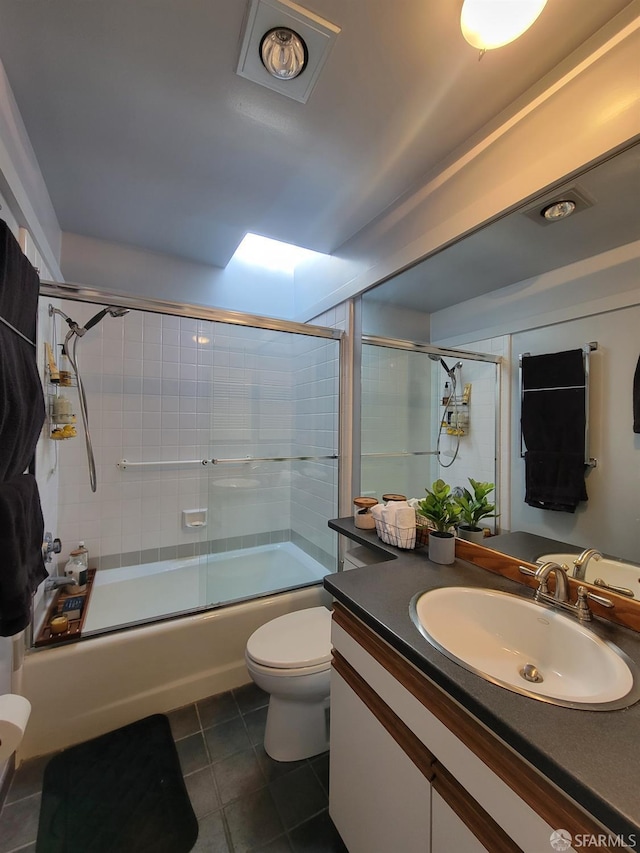 full bathroom featuring vanity, toilet, tile patterned floors, a skylight, and combined bath / shower with glass door