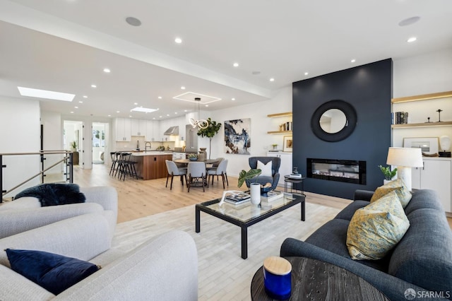 living room featuring light hardwood / wood-style floors, sink, and a skylight