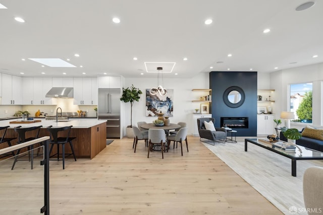 kitchen featuring light wood-type flooring, white cabinetry, a breakfast bar, and an island with sink