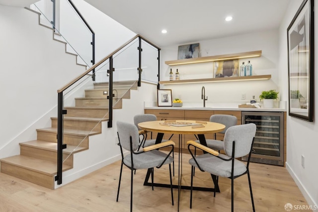 dining area featuring indoor wet bar, light wood-type flooring, and wine cooler