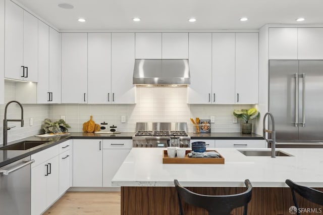 kitchen with sink, stainless steel appliances, a breakfast bar area, and range hood