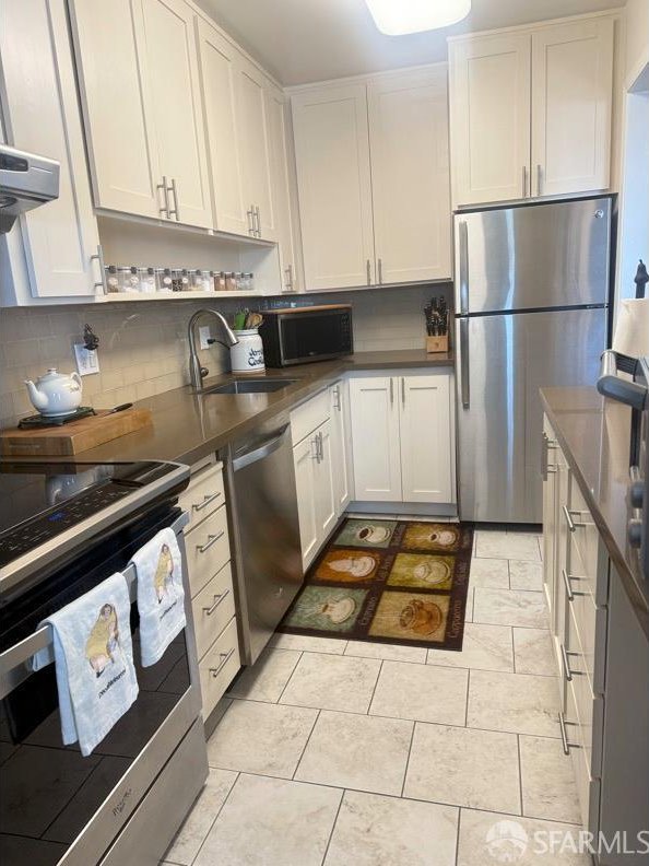 800 N Delaware St Unit 316, San Mateo, CA 94401 - kitchen featuring appliances with stainless steel finishes, a sink, dark countertops, white cabinetry, and decorative backsplash