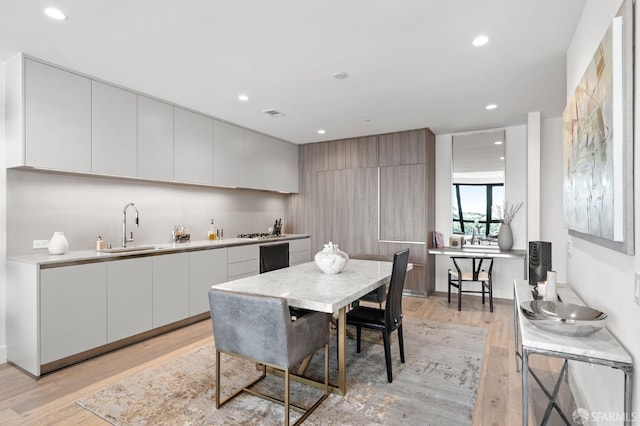kitchen featuring light countertops, modern cabinets, a sink, and light wood-style floors