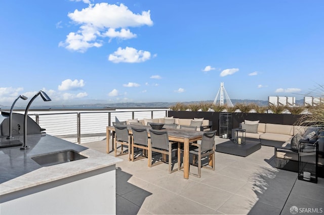 view of patio / terrace with a water view, exterior kitchen, an outdoor hangout area, and outdoor dining space
