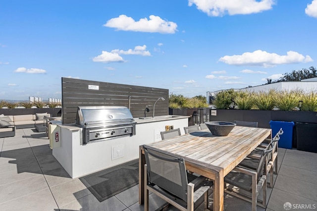 view of patio featuring grilling area, a sink, outdoor dining space, and exterior kitchen
