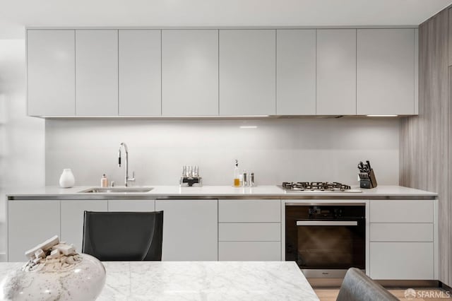 kitchen featuring a sink, modern cabinets, stainless steel gas stovetop, and oven