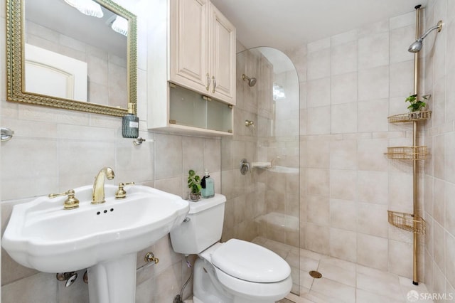 bathroom with tile walls, toilet, tasteful backsplash, and tiled shower