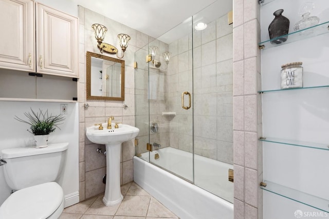 bathroom with tile walls, tile patterned flooring, shower / bath combination with glass door, and toilet