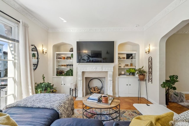 living room with built in features, ornamental molding, and a high end fireplace