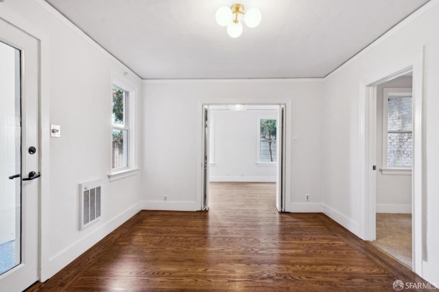 unfurnished room featuring a wealth of natural light, visible vents, baseboards, and wood finished floors