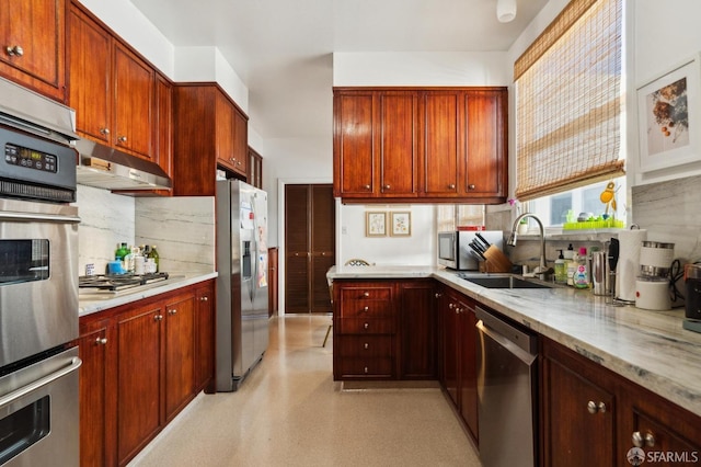 kitchen with stainless steel appliances, backsplash, a sink, light stone countertops, and under cabinet range hood